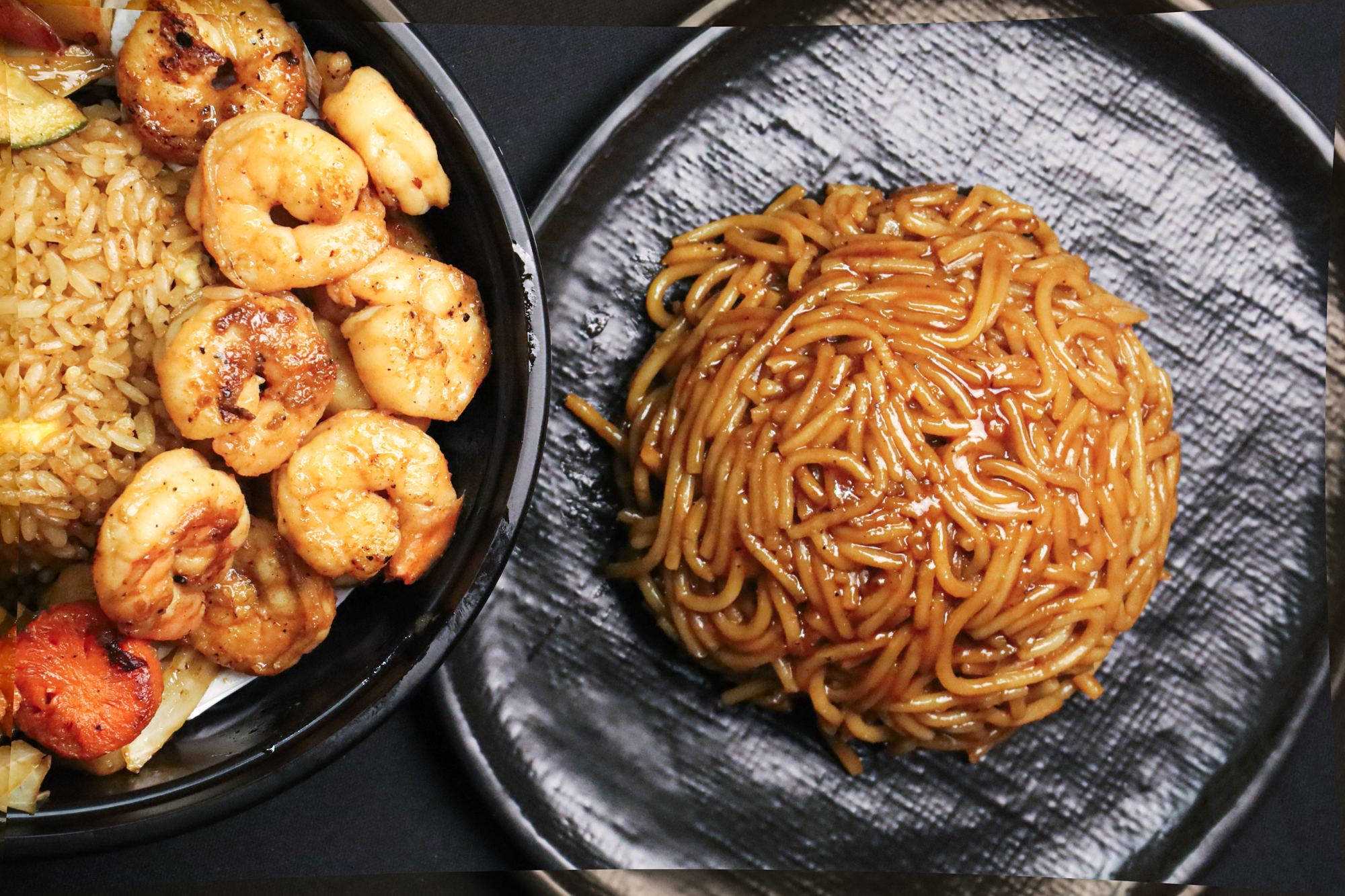 A shrimp bowl and a bowl of hibachi noodles on black slate