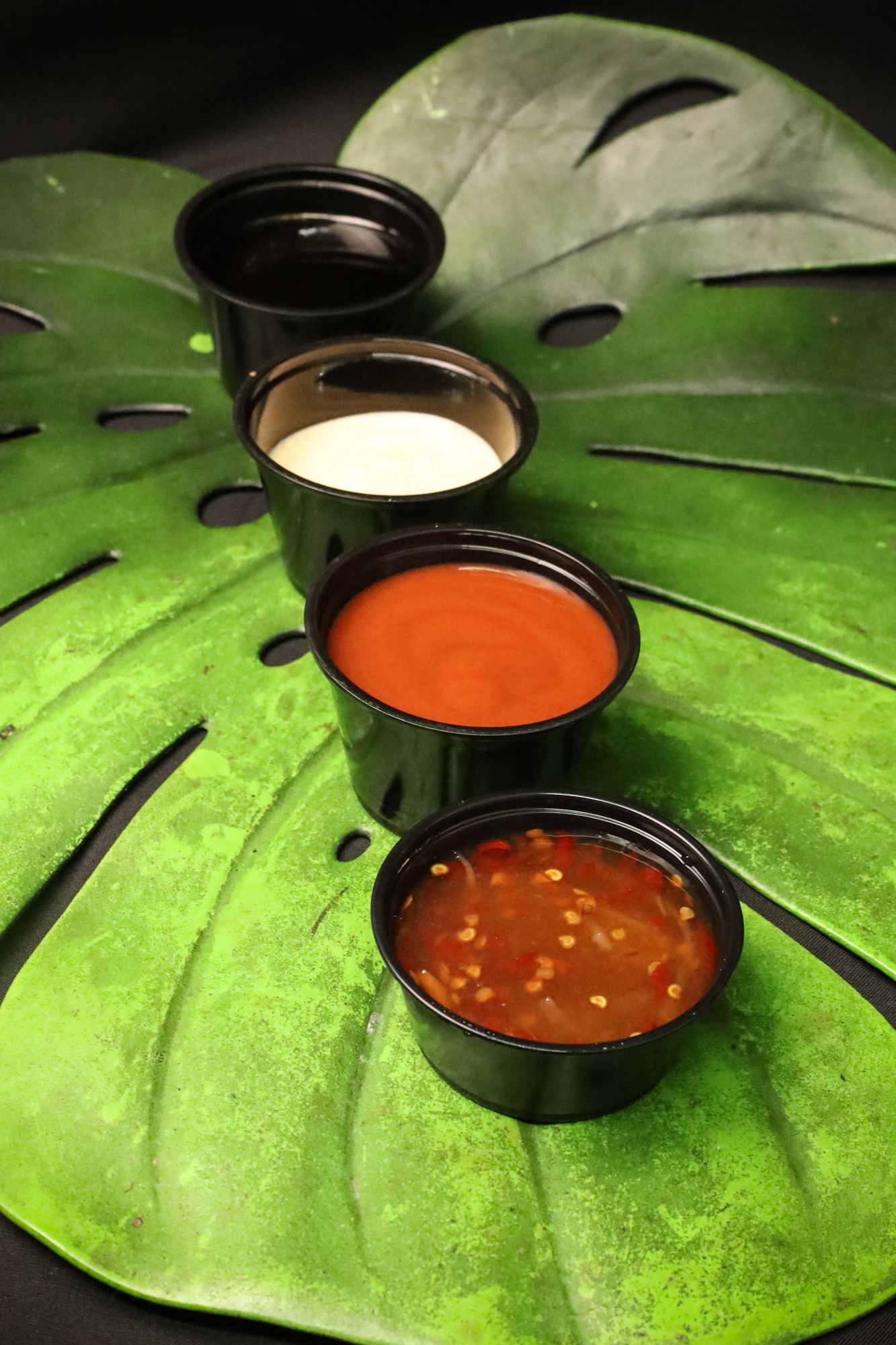 Three dipping sauces on a monstera leaf