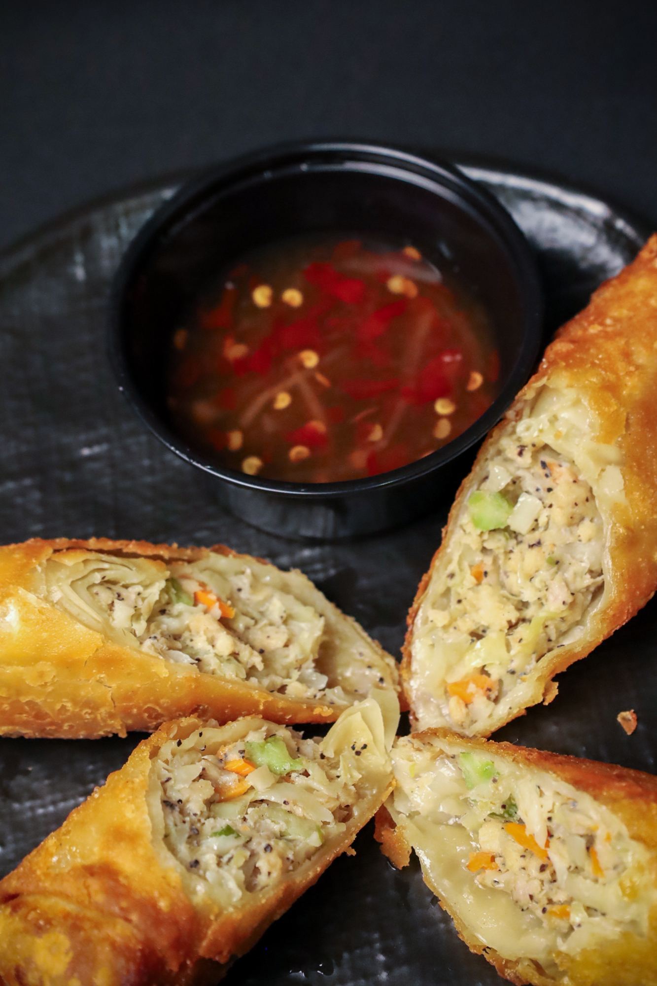 Spring rolls cut and fanned around a dipping sauce